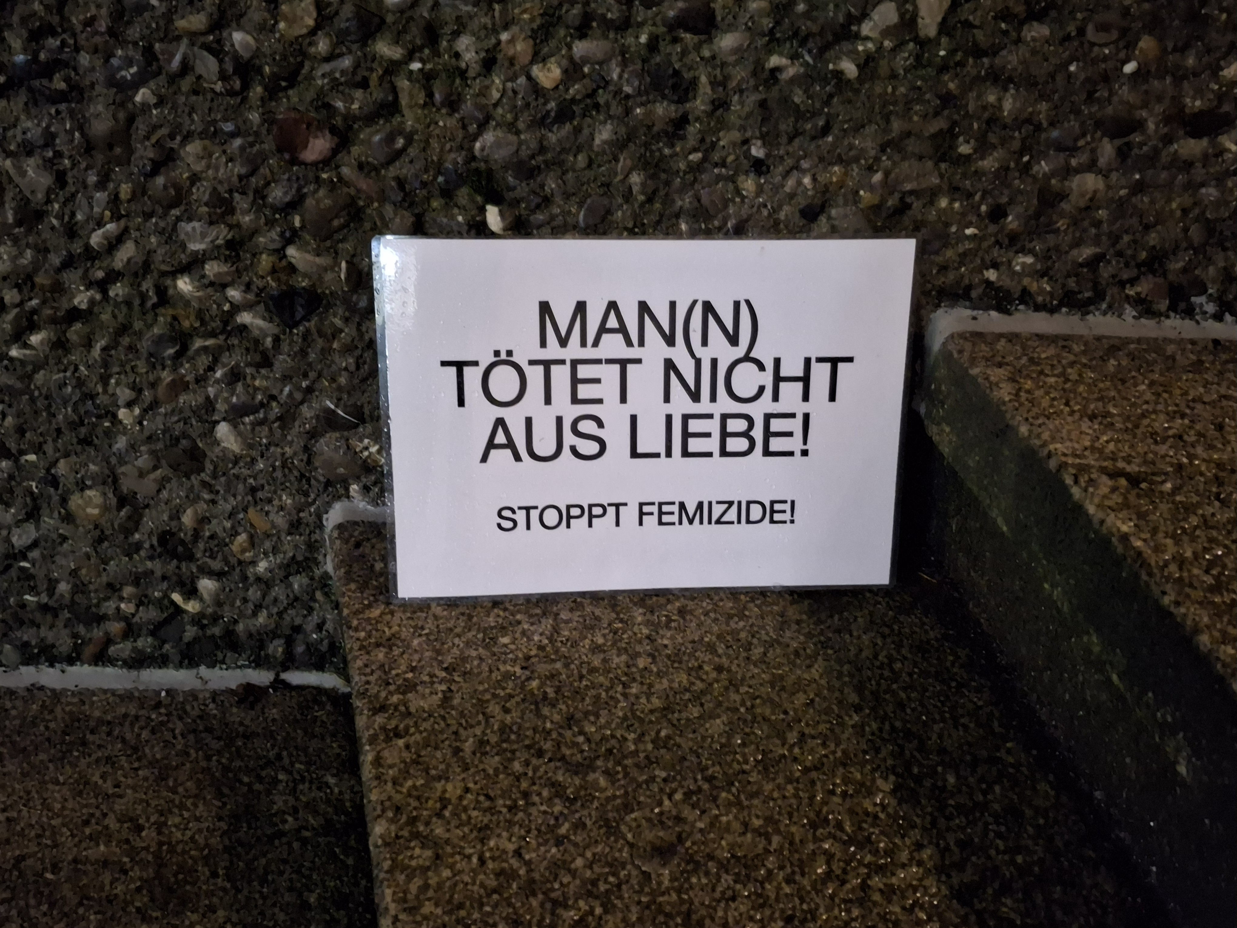 Kleines Plakat in Folie "Man(n) tötet nicht aus Liebe! Stoppt Femizide!"