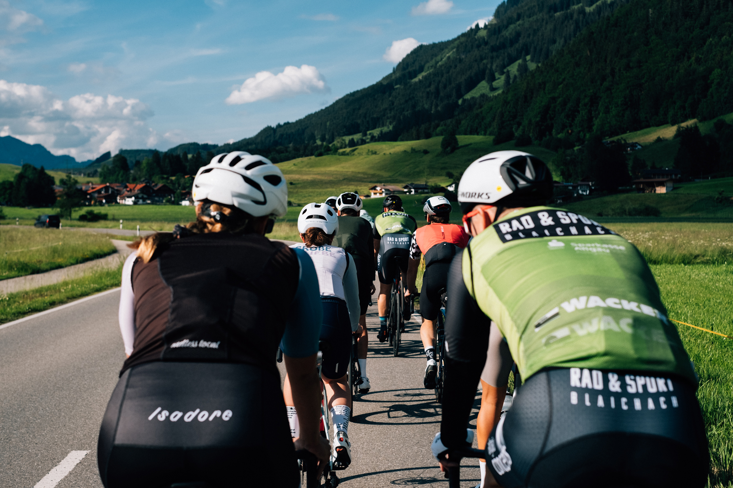 Rennradfahrergruppe in Hinteransicht auf einer Allgäuer Landstraße