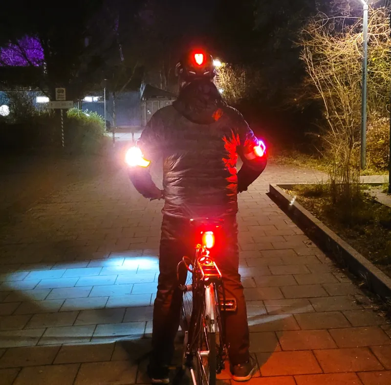 Radfahrer mit Rücklichtern am Rad, Helm und beiden Ellbogen.