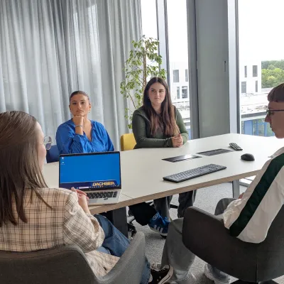 Vier Personen sitzen an einem Tisch zu einem Meeting.