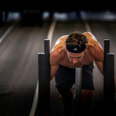 Sportler schiebt schweren Gegenstand.